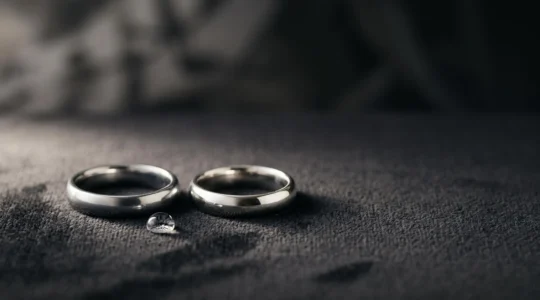 Dos anillos de compromiso casi idénticos, uno de platino y otro de oro blanco, colocados uno junto al otro sobre una superficie de terciopelo oscuro.