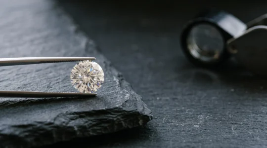 Diamante suelto sobre superficie oscura iluminado para revelar su talla, color y brillo, simbolizando la evaluación experta de las 4C