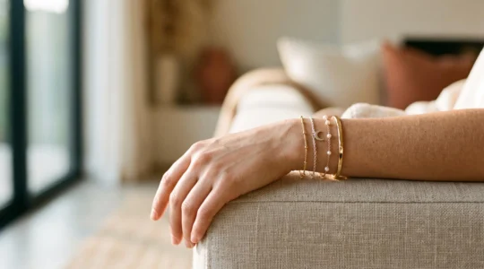 Muñeca femenina luciendo una combinación armoniosa de pulseras finas y un brazalete medio en tonos mixtos de metal