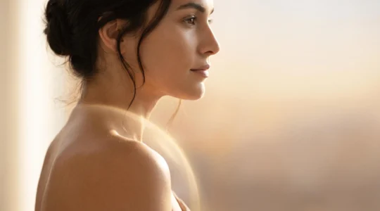 Rostro femenino con piel luminosa e hidratada, protegida del sol sin efecto graso ni residuo blanco.